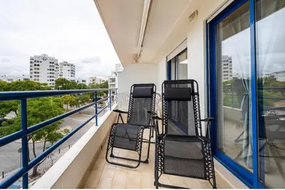 two chairs sitting on the balcony of a building at Quarteira beach house in Quarteira