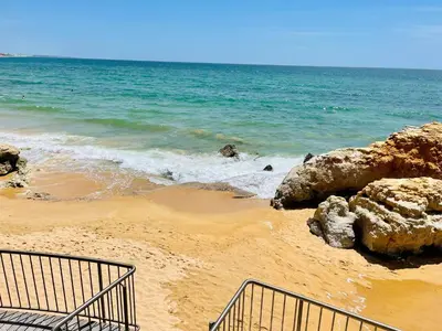 a sandy beach with rocks and the ocean at On The BEACH Stunning Apartment Albufeira Olhos de Água in Albufeira
