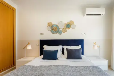 a bedroom with a bed with a blue headboard at On The BEACH Stunning Apartment Albufeira Olhos de Água in Albufeira