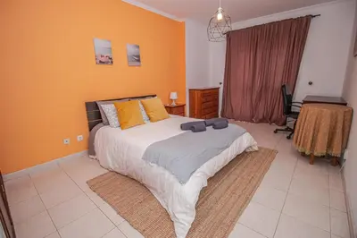 a bedroom with a large bed with orange walls at Charming Private Rooms in an Apartment A2 Penha - Faro in Faro