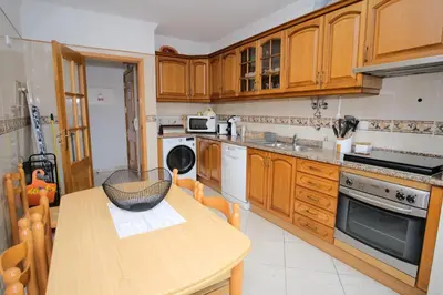 a kitchen with wooden cabinets and a wooden table at Apartamento T2 em condomínio fechado. in Albufeira