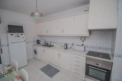 a kitchen with white cabinets and a white refrigerator at Charming Private Rooms in an Apartment A1 Penha - Faro in Faro