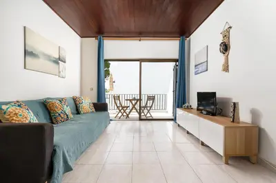 a living room with a blue couch and a television at Mouramar One bedroom apartment, with pool in Quarteira