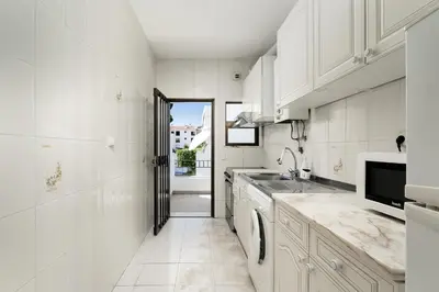 a white kitchen with a sink and a dishwasher at Mouramar One bedroom apartment, with pool in Quarteira