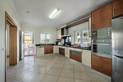 a large kitchen with wooden cabinets and stainless steel appliances at Villa Das Oliveiras amazing location walk to Marina restaurants beach in Albufeira