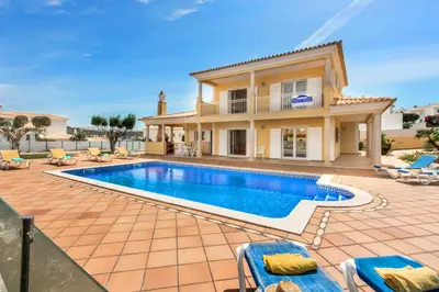 a villa with a swimming pool in front of a house at Villa Das Oliveiras amazing location walk to Marina restaurants beach in Albufeira