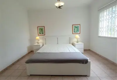 a white bedroom with a bed and two night stands at Vila Rosada in Quarteira