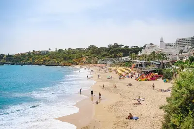 a group of people on a beach near the ocean at Shiny Central Flat - Pool in Albufeira