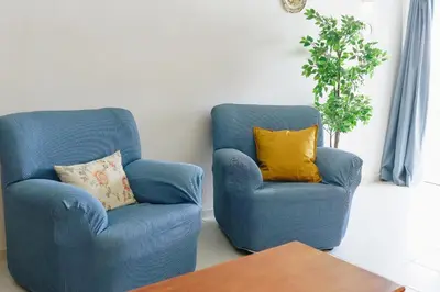 two blue chairs with yellow pillows in a living room at Shiny Central Flat - Pool in Albufeira