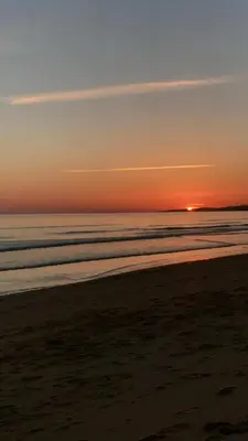 a sunset on a beach with the ocean at Golden Blue Beach Falésia Apartment in Albufeira