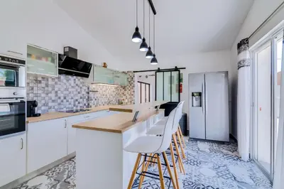 a kitchen with white cabinets and a counter with stools at Villa Rimbaud in Albufeira