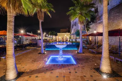 a fountain in the middle of a courtyard with palm trees at Vila Origens Boutique Hotel Albufeira – Adults Only in Albufeira