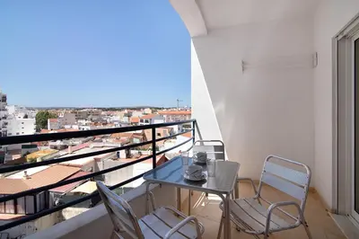 a table and chairs on a balcony with a view at Quarteira Beach iii in Quarteira