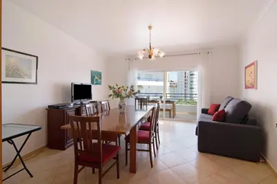 a dining room and living room with a table and chairs at Quarteira Beach iii in Quarteira