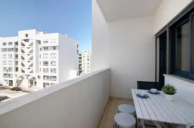 a balcony with a table and chairs and a building at Quarteira Beach I in Quarteira