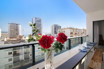 a vase with red roses on a table on a balcony at Quarteira Beach I in Quarteira