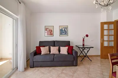 a living room with a gray couch with red pillows at Quarteira Beach ii in Quarteira