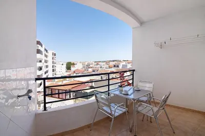 a dining room with a table and chairs on a balcony at Quarteira Beach ii in Quarteira