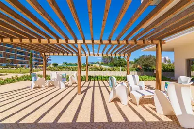 a group of white chairs under a wooden pergola at Marvell Design with heated pool&Playground in Albufeira
