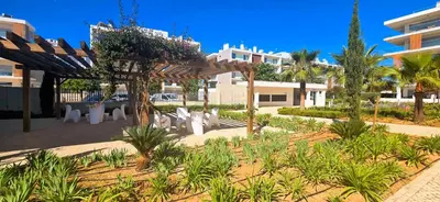a garden with white chairs and trees and a building at Marvell Design with heated pool&Playground in Albufeira
