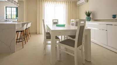 a white kitchen with a white table and chairs at Villa O Sonho do Algarve - Private Swimming Pool - BY BEDZY in Albufeira