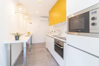 a kitchen with white cabinets and a microwave and a table at Avenue 41 Guest House in Faro
