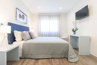 a white bedroom with a large bed and a window at Avenue 41 Guest House in Faro