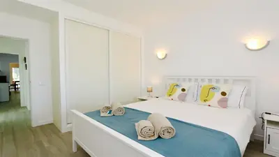 a white bedroom with a bed with slippers on it at Vila Renascer-CleverDetails, few minutes from the center, quiet area in Vilamoura