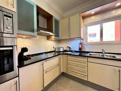 a kitchen with white cabinets and a black dog sitting on the counter at Vilamoura Victoria Gardens With Pool by Homing in Vilamoura