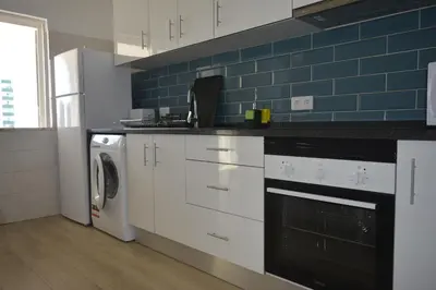 a kitchen with a washing machine and a blue tile wall at Apartamento Azul in Quarteira
