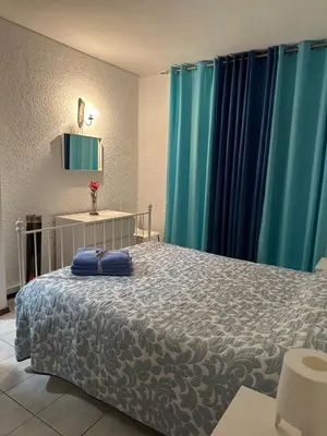 a bedroom with a white bed and blue curtains at Quarteira Home Beach Férias Tranquilas a 1KM da Praia Totalmente Renovado in Quarteira