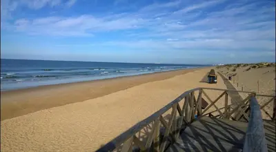 a sandy beach with a fence and the ocean at Scarlet's Place - 1 bed Victory Village Quinta Do Lago - beach, nature, lakes in Quinta do Lago