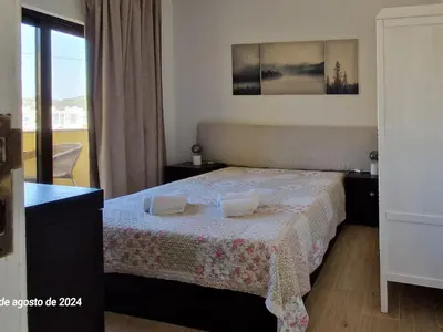 a bedroom with a bed with a table and a window at Apartamento Solaris T1 - Férias Albufeira in Albufeira