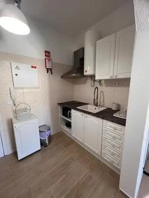 a small kitchen with white cabinets and a sink at Apartamento Solaris T1 - Férias Albufeira in Albufeira