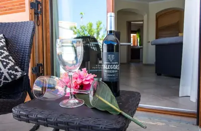 a bottle of wine and a glass and flowers on a table at Villa Girassol - By Dalma Portuguesa in Albufeira