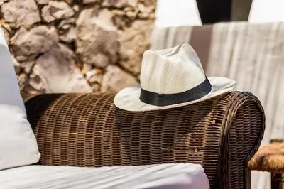 a hat sitting on top of a wicker chair at Casas Barulho - Villa Jacaranda A8 in Albufeira