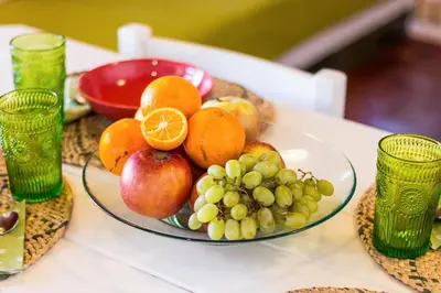 a plate of fruit on a table with glasses at Casas Barulho - Villa Jacaranda A8 in Albufeira