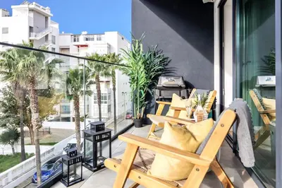 a cat sitting in a chair on a balcony at Stylish Modern Beachside Apartment with Pool & Seaview in Quarteira