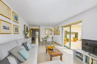 a living room with a white couch and a tv at Penthouse Escape with Large Terrace, Pool & Garden in Quarteira