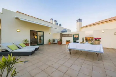 a patio of a house with two couches and a table at Penthouse Escape with Large Terrace, Pool & Garden in Quarteira