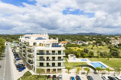 an aerial view of a large white building with a parking lot at Penthouse Escape with Large Terrace, Pool & Garden in Quarteira