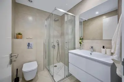 a bathroom with a shower and a toilet and a sink at Bright Modern Beachside Apartment with Pool & Seaview in Quarteira