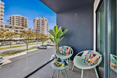 a balcony with two chairs and a view of the city at 2-Bedroom Beachside Apartment with Pool & Parking in Quarteira