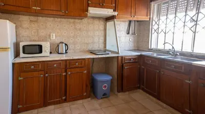 a kitchen with wooden cabinets and a sink and a microwave at Apartamento Tio Pedro - by bedzy in Albufeira