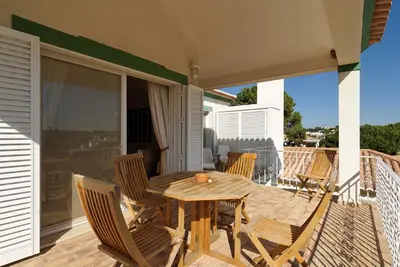 a wooden table and chairs on the porch of a house at Tulio 2 Bedroom Luxury Apartment located in Encosta Do Lago in Quinta do Lago