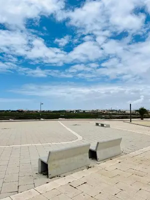 a bench in a parking lot with a cloudy sky at Fisherman´s Cave in Faro