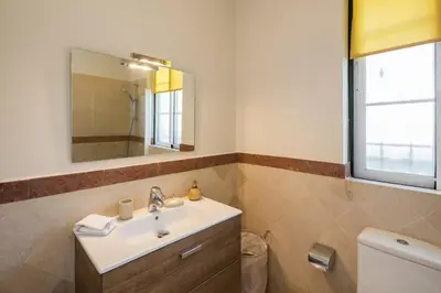 a bathroom with a sink and a mirror and a toilet at Sera - Luxury 3 bedroom apartment with pool, golf,beach in Ludo