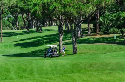 a group of people playing golf on a golf course at Sunshine - PINHEIROS ALTOS in Quinta do Lago