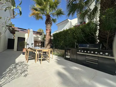 a patio with a table and a kitchen and a palm tree at Sunshine - PINHEIROS ALTOS in Quinta do Lago