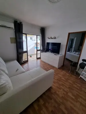 a living room with a white couch and a television at AAA T2 Awesome Albufeira Apartments Piscina Marina in Albufeira